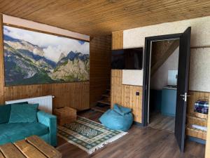 a living room with a green couch and a mountain mural at Mtaura Cabins in Kazbegi