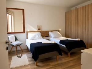 a bedroom with two beds and a chair and a mirror at Harba - An Escape at Fort Chambray in Għajnsielem +16 photos