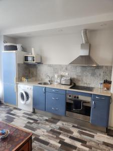 a kitchen with blue cabinets and a washer and dryer at Apartamento Sol in Suances