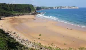 a beach with people on the sand and the ocean at Apartamento Sol in Suances