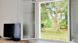 a television sitting next to a window with a tree at Proche de la plage, très bien situé in Ondres