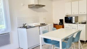 a white kitchen with a white table and chairs at Proche de la plage, très bien situé in Ondres
