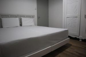 a white bed with white pillows in a bedroom at Maison des Anges in Mahébourg