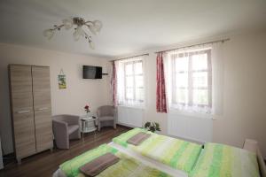 a bedroom with a bed and a chair and two windows at Pension Chalupka ll with a panoramic view of Spiš Castle in Spišské Podhradie