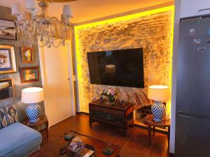 a living room with a tv on a stone wall at La Terraza del Castillo- Playa de Rota in Rota