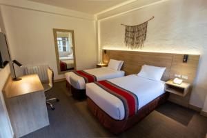 a hotel room with two beds and a mirror at Ecoterra Essentials San Blas in Cusco