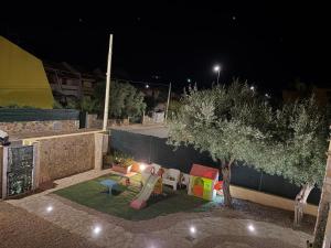 a playground with a slide and a tree at night at Villaluciana Solanas in Solanas