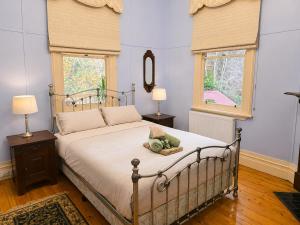 a bedroom with a bed with two lamps and two windows at Charnwood Cottages in Warburton