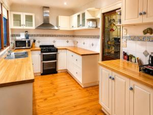 a kitchen with white cabinets and wooden floors at Charnwood Cottages in Warburton