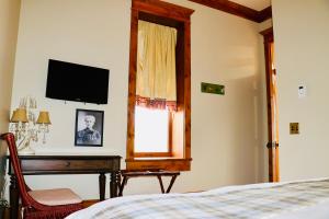 a bedroom with a bed and a desk and a television at The Kleemann House-1883 Historic Downtown Hotel in Custer
