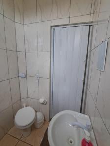 a white bathroom with a toilet and a sink at Suite Nomar 1 in Brotas