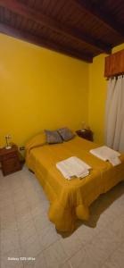 a yellow bedroom with a bed with towels on it at Alojamiento Dina in Puerto Madryn