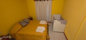a yellow room with a bed with towels on it at Alojamiento Dina in Puerto Madryn +4 photos