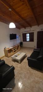 a living room with black furniture and a flat screen tv at Alojamiento Dina in Puerto Madryn
