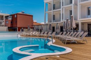 a swimming pool with chairs and umbrellas next to a building at Royal Nidri Suites in Nydri