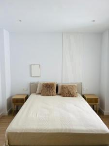 a white bedroom with a large bed with two tables at Palacios Centro - El Puerto in El Puerto de Santa María