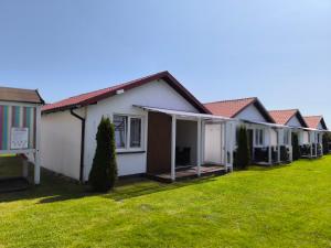 a row of houses in a yard with grass at Domki letniskowe Reda in Rusinowo