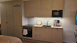 a kitchen with brown cabinets and a clock on the counter at Fabbrica's new and elegant apartment in Turku