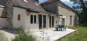 a patio with a table and chairs outside of a house at La maison de Fée-Licité in Salignac Eyvigues