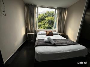 a small bedroom with a bed with a window at Hotel Aura Nutibara in Medellín