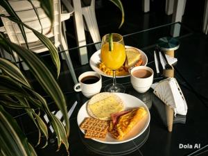 a table with two plates of food and a glass of orange juice at Hotel Aura Nutibara in Medellín