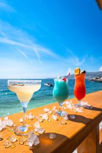 three cocktails sitting on a table near the ocean at The Hidden Sea Rooms in Sarandë