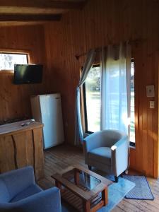 a living room with a couch and a chair and a table at Rio liucura cabañas in Collentañe
