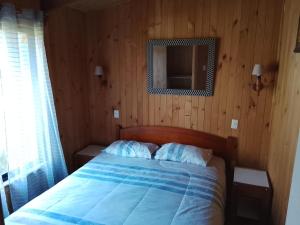 a bedroom with a bed with a wooden wall at Rio liucura cabañas in Collentañe