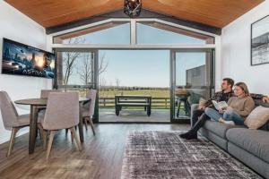 a man and woman sitting on a couch in a living room at Black Label Retreats in Gisborne