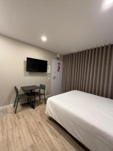 a bedroom with a bed and a table and a television at Casa dos Limos - Apartments in Foz do Arelho