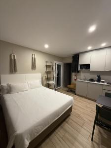 a bedroom with a large white bed and a kitchen at Casa dos Limos - Apartments in Foz do Arelho