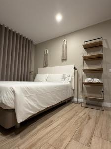 a bedroom with a white bed and a book shelf at Casa dos Limos - Apartments in Foz do Arelho
