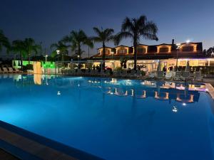 a swimming pool at night with people standing around it at Kavani in Pizzo