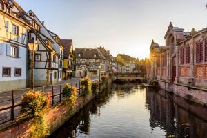 a river in a city with buildings and a bridge at LE LYNX HAUSSMANIEN appartement tout confort, climatisé avec parking privé, à deux pas du centre in Colmar