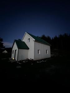 a white barn with a green roof at night at Everpine house in Žabljak