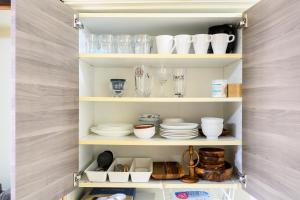 a kitchen pantry with plates and dishes on shelves at yadobankkukomae19 in Fukuoka