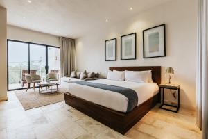 ein Hotelzimmer mit einem großen Bett und einer Couch in der Unterkunft The Strabon Tulum in Tulum
