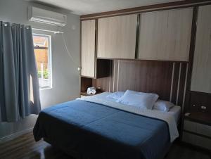 a bedroom with a bed with a blue blanket and a window at Casa Zibell centro de Pomerode in Pomerode