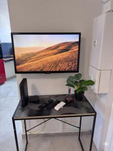 a monitor on a wall with a desk with a keyboard at Cocon du Souffleur in Port-Louis