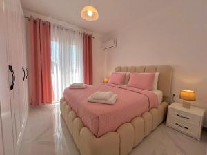 a bedroom with a large bed with pink sheets at Villa Joel in Kefallonia