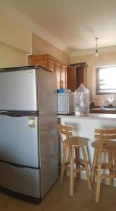 a kitchen with a refrigerator and a table and chairs at Chalet with roof pool view in Dawwār ‘Abd Allāh +2 photos