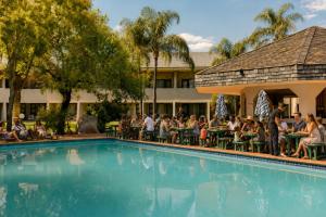 a group of people sitting around a pool at a hotel at Sundown Country Estate in Boshoek