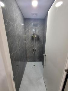 a bathroom with a shower with gray tiles at MAOS Building in Batangas City