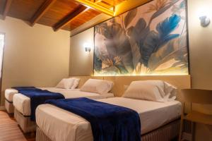 three beds in a room with a painting on the wall at Hotel El Arroyo in Caracas +78 photos