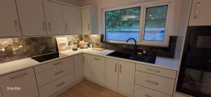 a kitchen with white cabinets and a sink and a window at Rosmore Newport in Newport