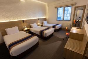 a hotel room with two beds and a television at Ecoterra Essentials San Blas in Cusco +55 photos