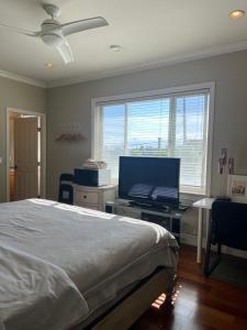 a bedroom with a bed and a desk with a flat screen tv at A cozy en-suite on the second floor with independent entranceclose to YVR in Richmond