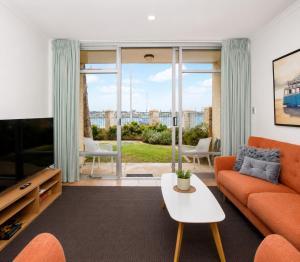 a living room with an orange couch and a tv at Mariners Lookout Absolute Harbour Views in Fremantle