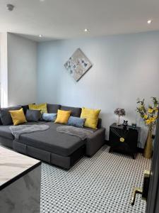a black couch in a living room with yellow pillows at Dove & Gold in Gloucestershire