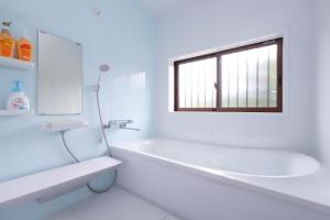 a white bathroom with a tub and a window at サウナ&ステイ吉日荘-益子町のプライベートサウナ付の貸切古民家 BBQ 高速Wi-fi in Mashiko